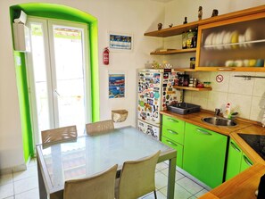 A kitchen with a green countertop, a glass table, and a refrigerator covered in stickers. - Croparadise Central (Split)