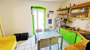 Uma cozinha compacta com área de refeições, armários verdes e uma geladeira decorada com imãs.