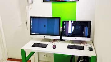Una habitación con un escritorio que tiene dos monitores, un teclado y un ratón. Un cuadro llamativo adorna la pared sobre el escritorio.