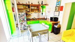 Uma cozinha compacta com uma mesa de jantar, armários verdes e micro-ondas.