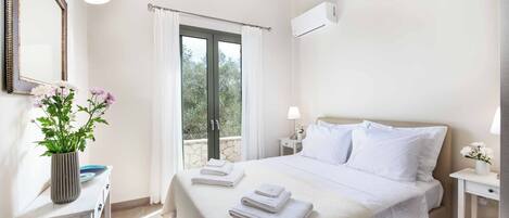 Une chambre d’hôtel avec un lit, une table de chevet, une lampe, un miroir et une fenêtre avec des rideaux.