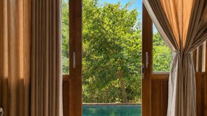 A room with a view of a swimming pool and greenery outside. - J Villa Sigiriya - Private Pool Chalets (sigiriya)