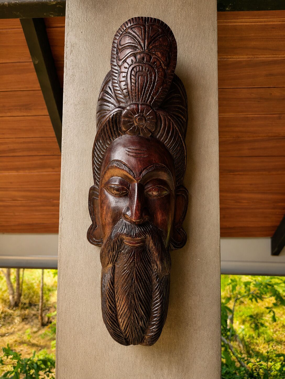 A carved wooden headpiece mounted on a wall.