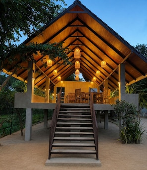 A covered outdoor seating area with a staircase leading up to it, surrounded by plants and trees. - J Villa Sigiriya - Private Pool Chalets (sigiriya)