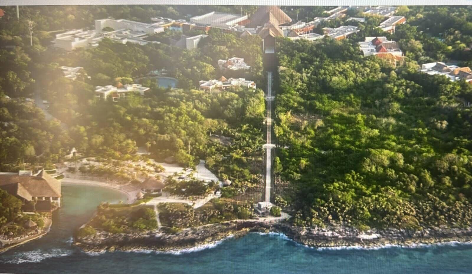 An aerial view of a coastal area with a lighthouse, residential buildings, and a beach.