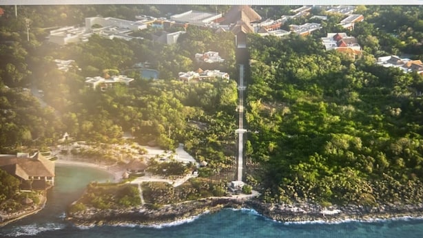 An aerial view of a coastal area with a lighthouse, residential buildings, and a beach.