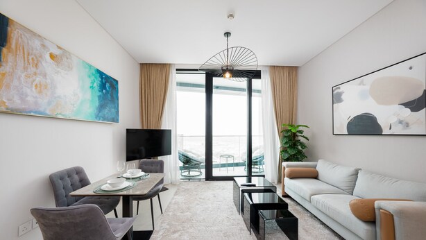 A modern living room with a dining area, a large window, and a view of the outdoors. - Chic Address JBR Haven w Marina View (Dubai)