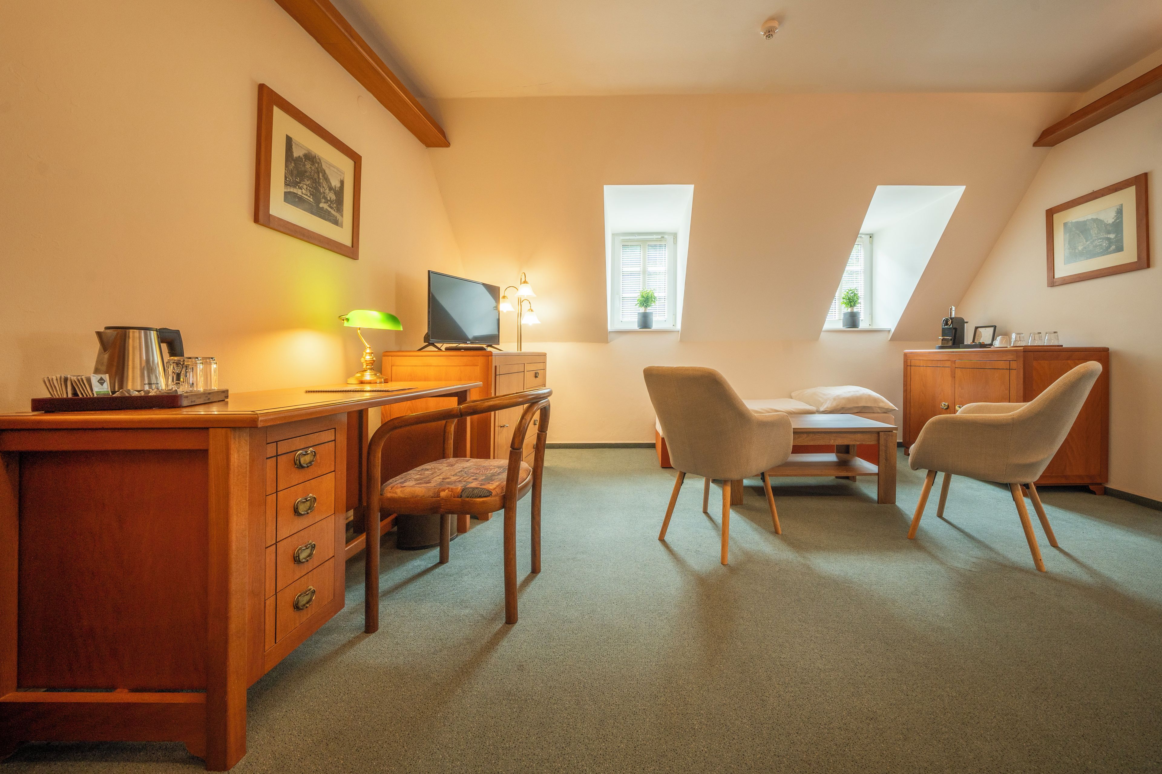 Een gezellige kamer met een houten bureau, twee stoelen, een televisie en een klein tafeltje.