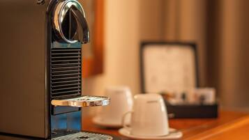 A coffee machine on a wooden table with a cup and saucer, a napkin holder, and a small object on the table.