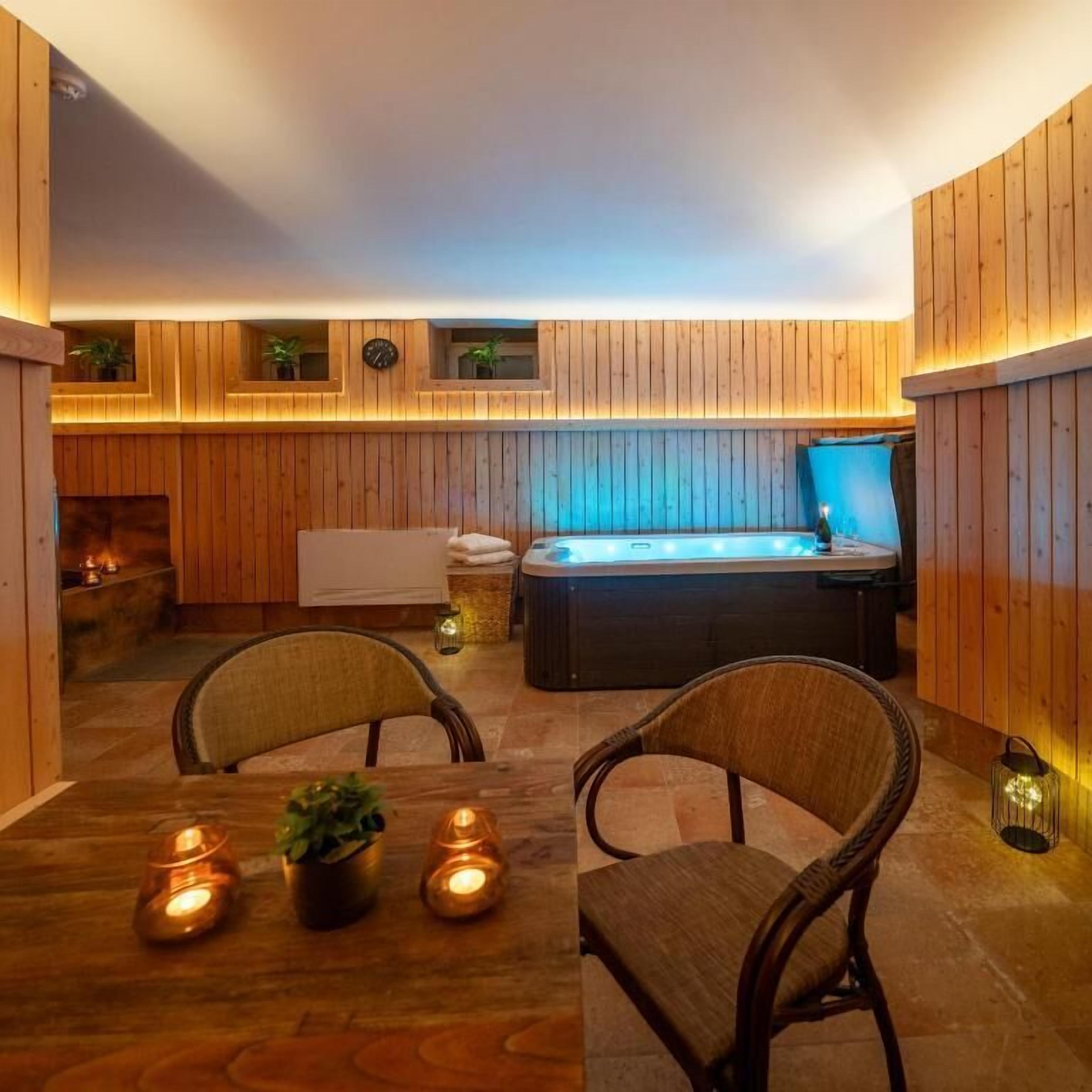 Una habitación acogedora con un panel de madera, un jacuzzi y una mesa de comedor con velas.