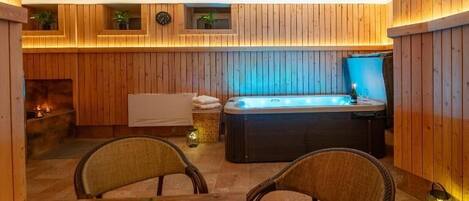 Una habitación acogedora con un panel de madera, un jacuzzi y una mesa de comedor con velas.