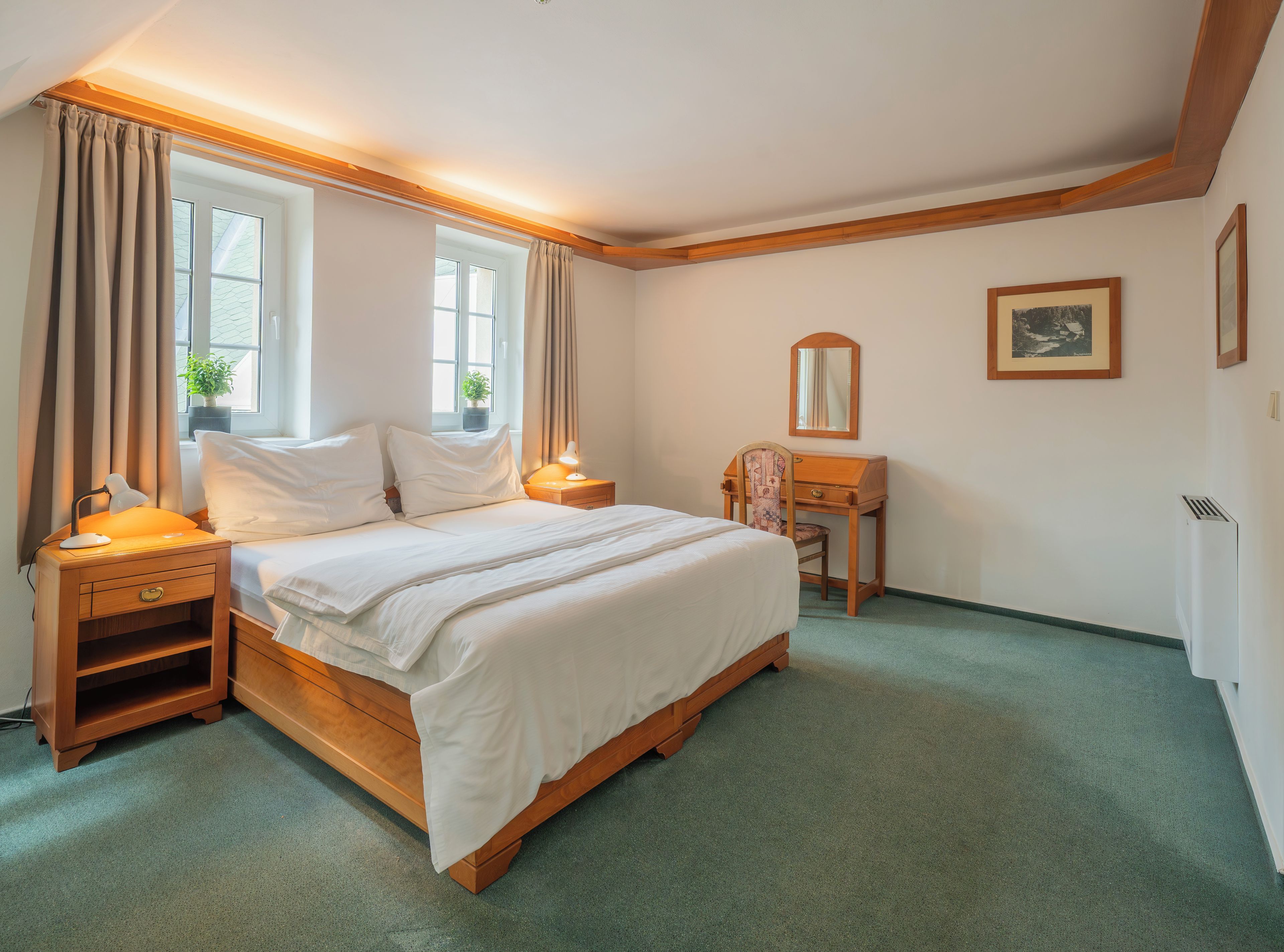Une chambre à coucher bien rangée, avec un lit, des tables de chevet, un bureau et une chaise.