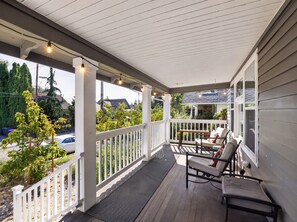 A covered porch with a railing, outdoor seating, and string lights. - Inner Portland Craftsman | Hot Tub & Pool Table (Portland)