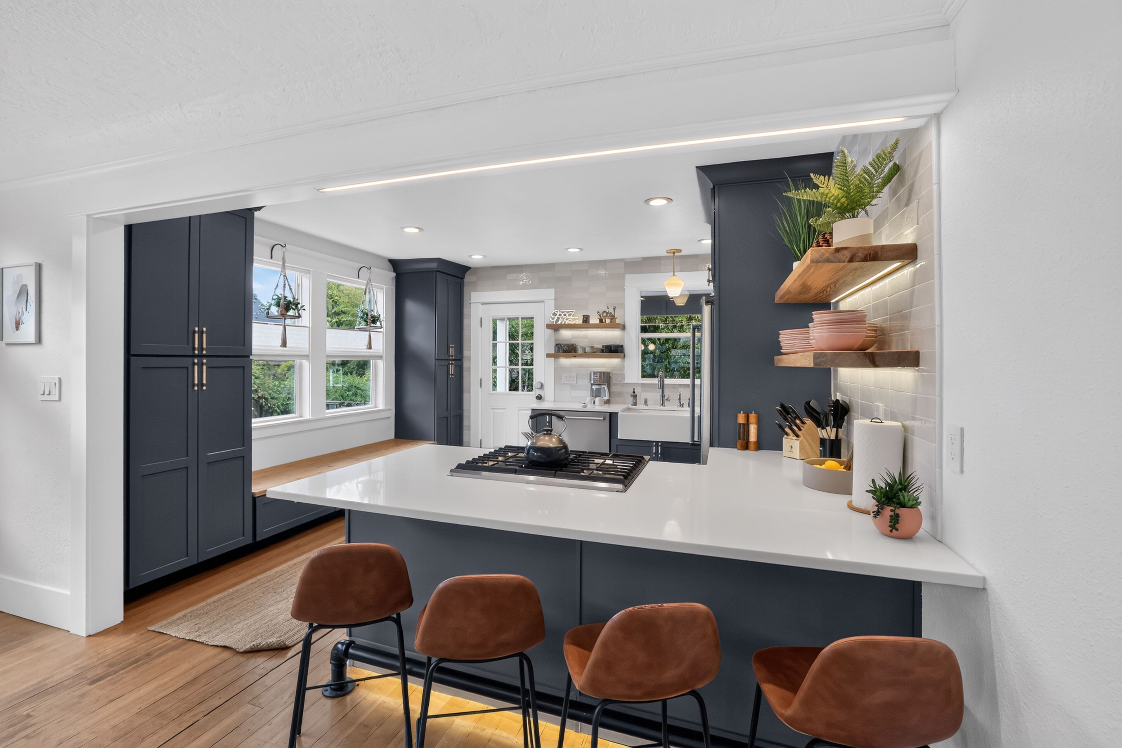 A modern kitchen with a central island, bar stools, and built-in shelving.