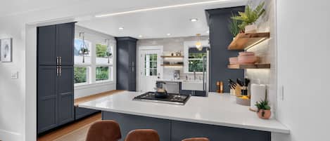 A modern kitchen with a central island, bar stools, and built-in shelving.