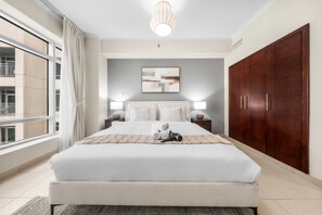 A modern bedroom with a large bed, two bedside lamps, a wooden wardrobe, and a view of the outside. - Free Housekeeping Visits During Your Stay - Stayshort - Modern and Chic Studio in Downtown With Burj Khalifa Views (Dubai)