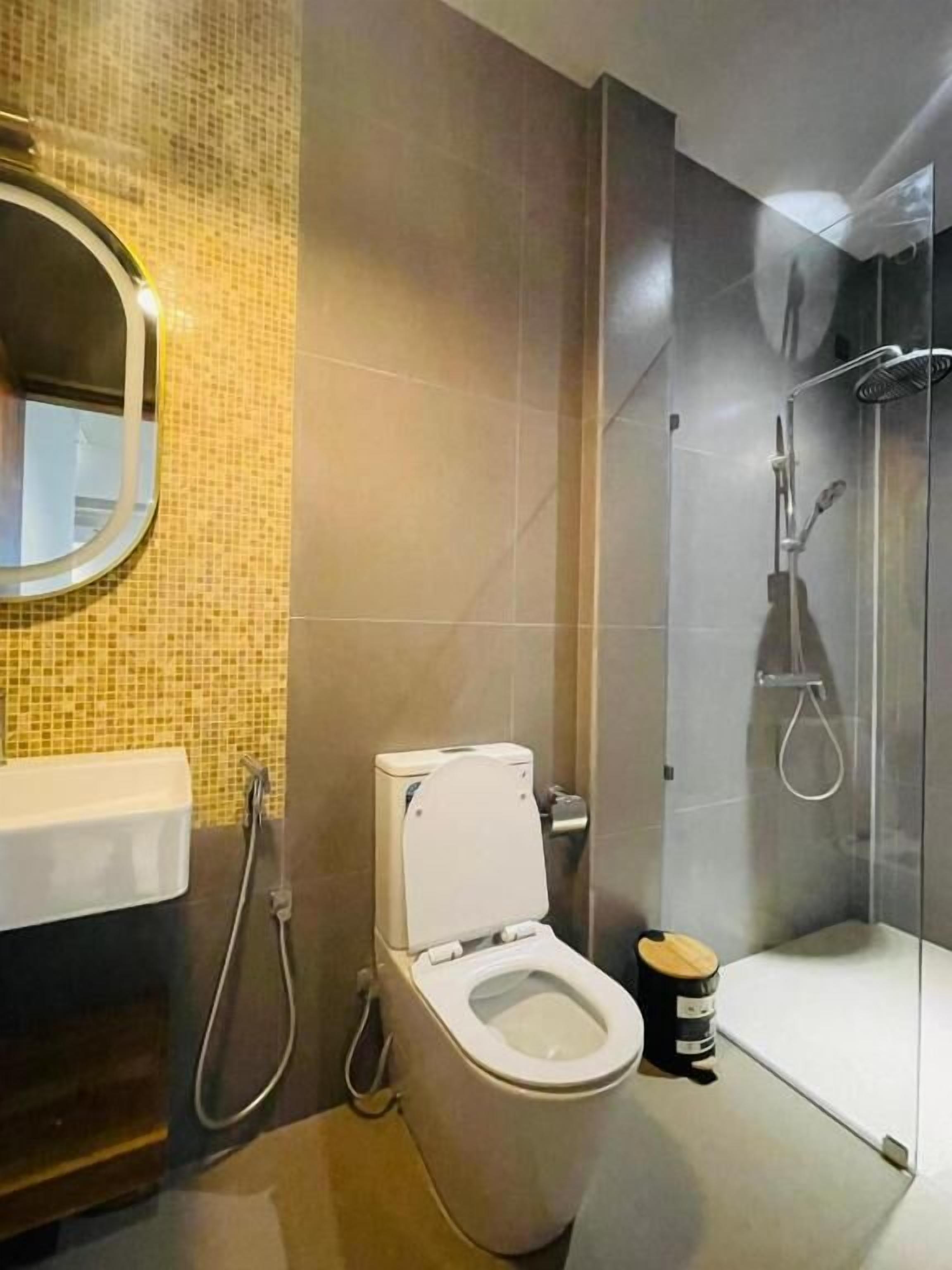 Un baño moderno con inodoro, ducha y cabina de ducha con paredes de vidrio.