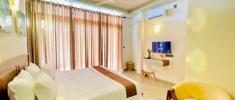 Une chambre d’hôtel avec un lit, un bureau, une chaise et un téléviseur.