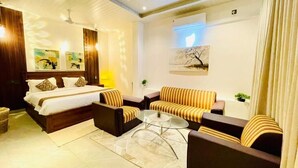 Una habitación de hotel con una cama, dos sofás, una mesita de café y obras de arte en las paredes.