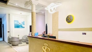 Un mostrador de recepción con un logo, un cartel en la pared y un cuadro enmarcado.