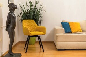 A room with a yellow armchair, a beige sofa with blue and yellow cushions, a green plant, and a statue. - Villa Astera with Privat Pool, 5 Bedrooms for 9 Guests, (Jesenice)