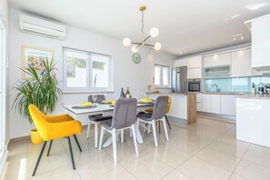 A modern kitchen with white cabinetry, a built-in oven, and a dining area with a table set for two. - Villa Astera with Privat Pool, 5 Bedrooms for 9 Guests, (Jesenice)