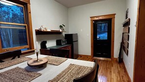 Comedor con una mesa lista para dos personas, un microondas y un refrigerador al fondo.