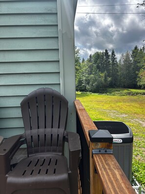 A porch with a chair and an air conditioning unit.