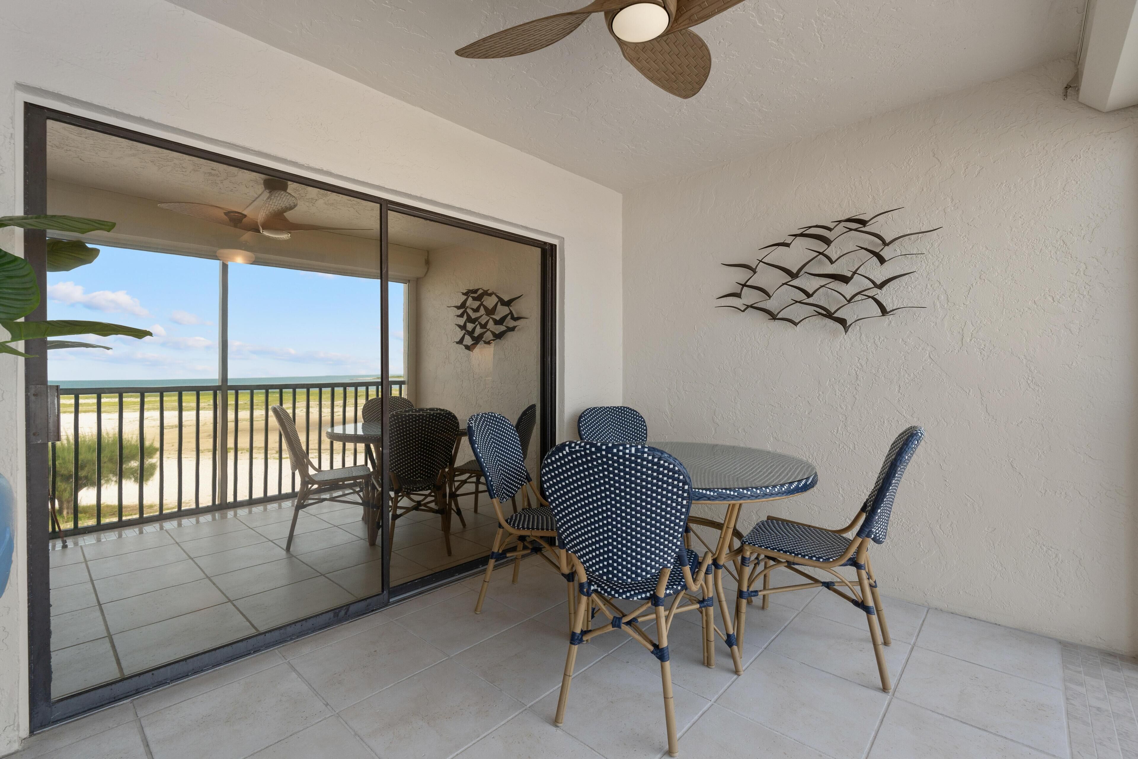 A room with a glass door leading to a balcony, a ceiling fan, and a wall-mounted decorative piece.