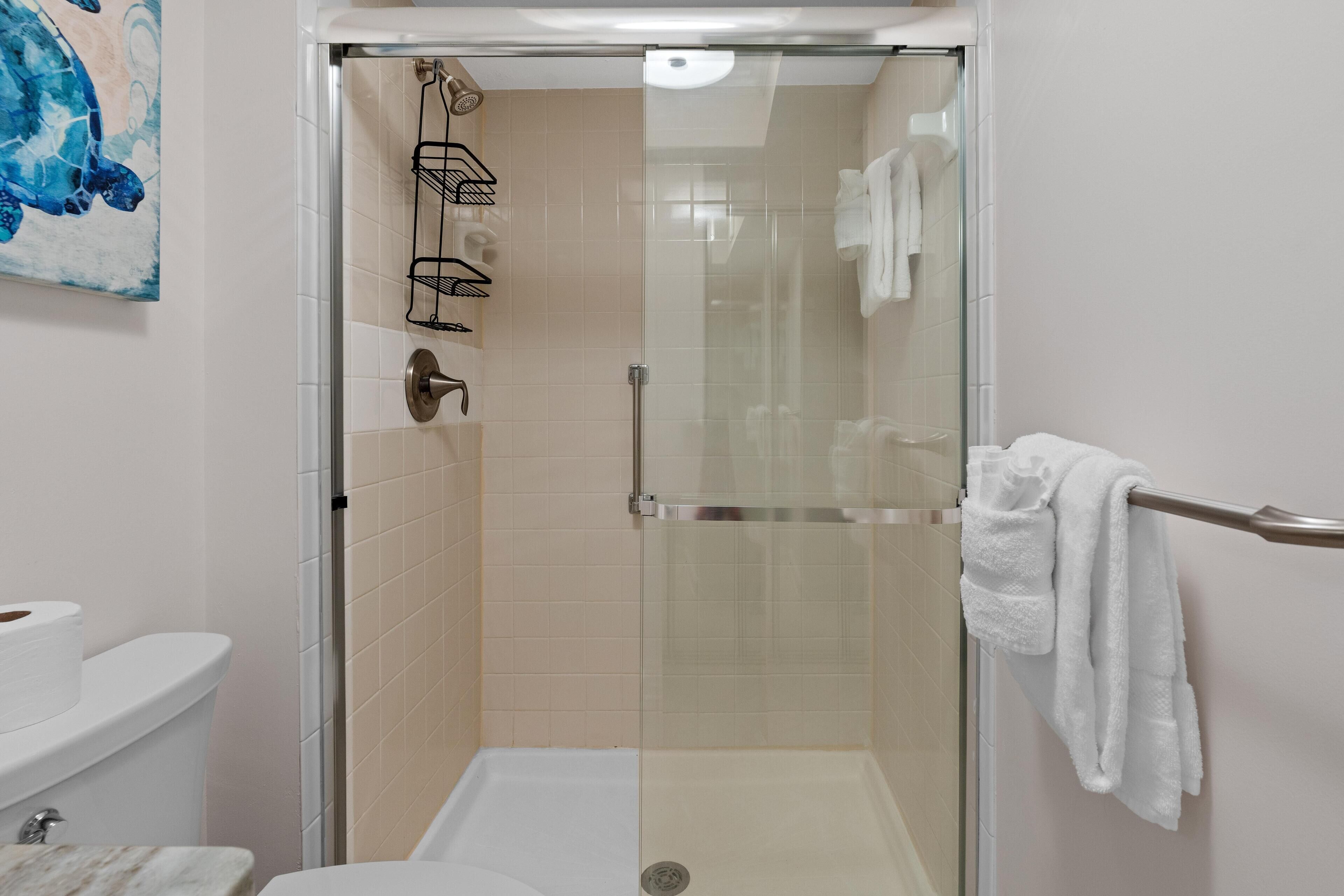 A glass-enclosed shower stall with a white towel on a towel rack.