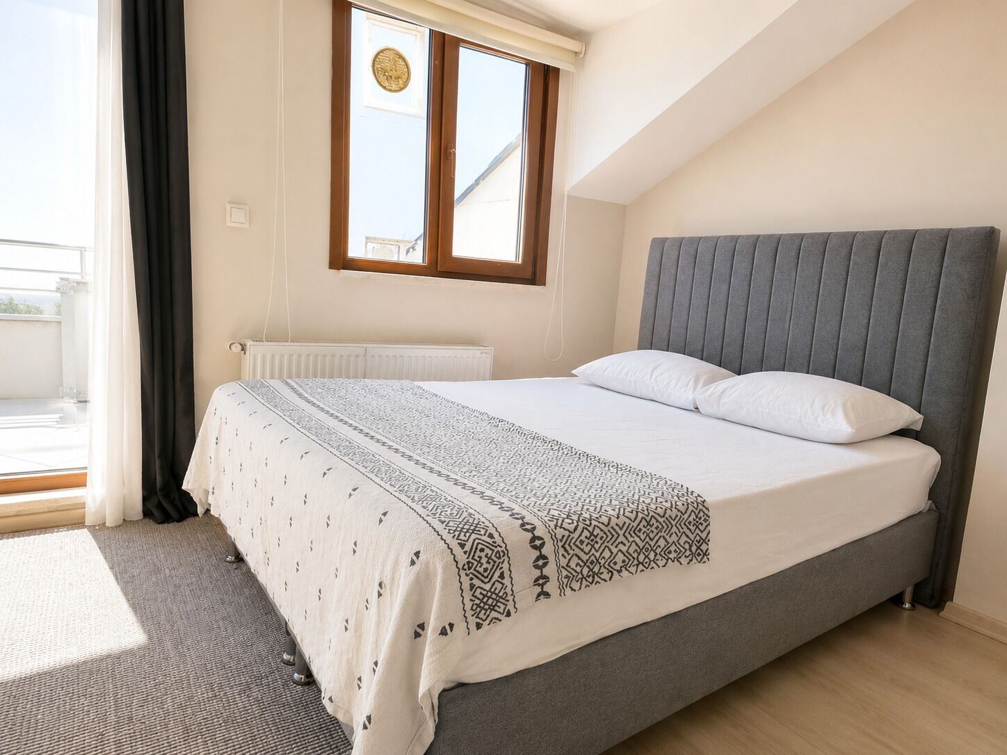 A bedroom with a bed, a window, and a radiator.