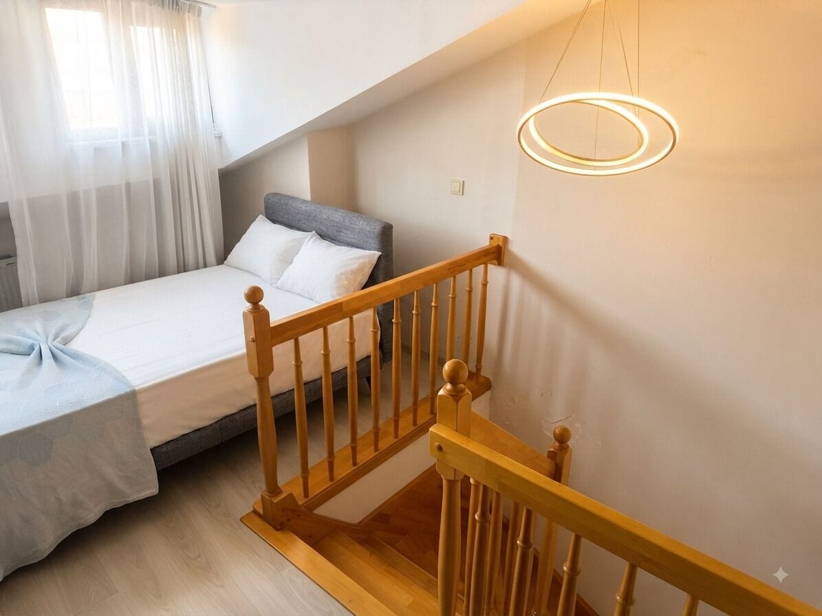 A bedroom with a bed, a wooden staircase, and a modern light fixture.
