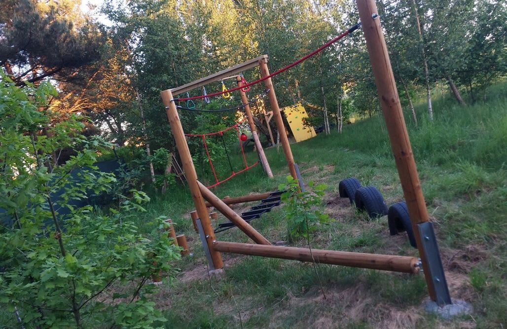 An outdoor wooden play structure in a wooded area.