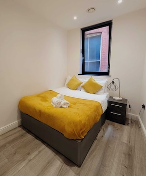 Ein modernes Schlafzimmer mit Bett, Kissen, Nachttisch und Lampe.