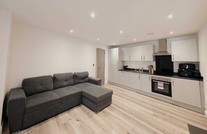 A modern kitchen with white cabinets, a black countertop, and a built-in oven. - City Centre Two Bedroom Apartment (Liverpool)