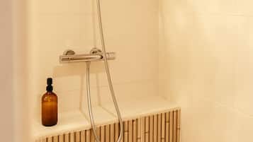 Een douche met een handdouche en bediening aan de muur.