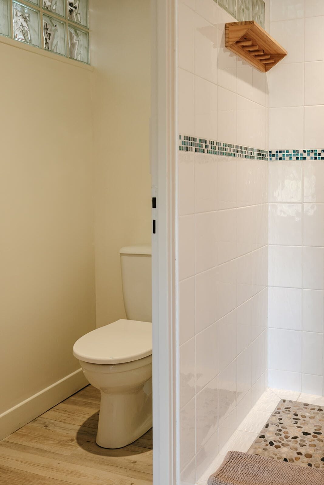 Une salle de bain comprenant des toilettes, un espace douche et un sol carrelé.