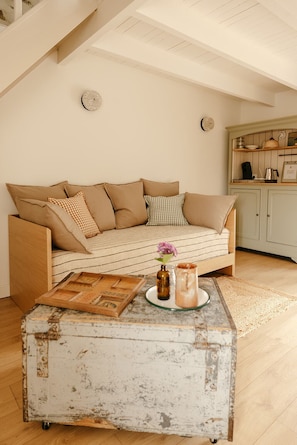 A cozy living room with a sofa, a coffee table, and a kitchen area in the background.