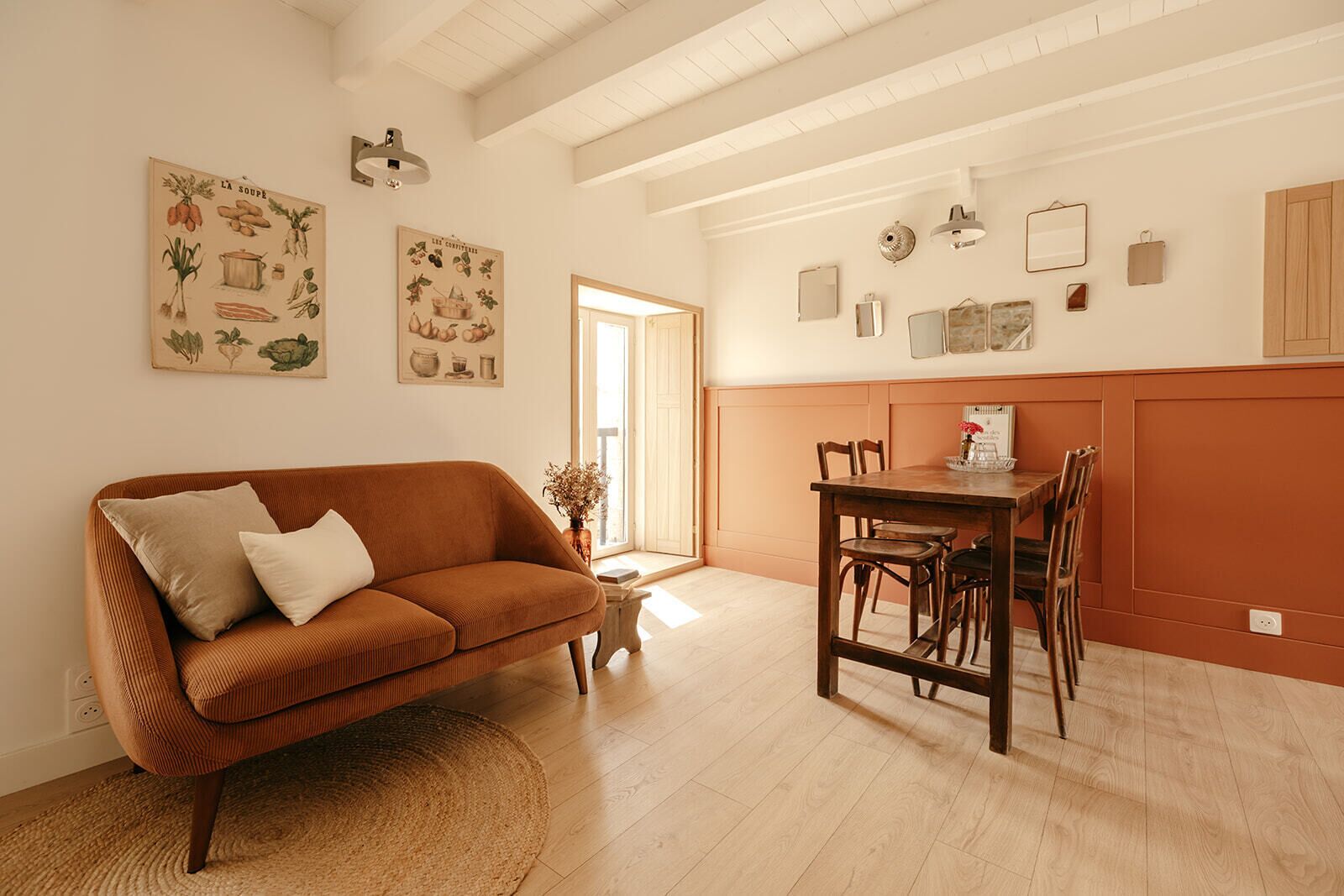 Een gezellige woonkamer met een bruine bank, een eettafel met stoelen en een klein bijzettafeltje.