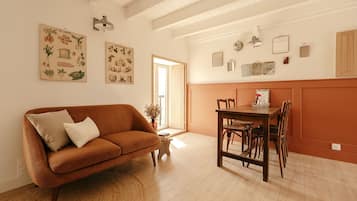 Een gezellige woonkamer met een bruine bank, een eettafel met stoelen en een klein bijzettafeltje.
