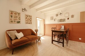 A cozy living room with a brown sofa, a dining table with chairs, and a small side table.