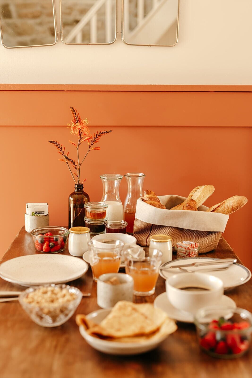 Une table de petit-déjeuner avec divers aliments, notamment du pain, des fruits et des boissons.