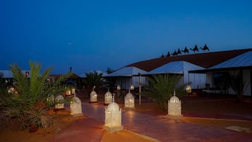 A pathway lined with illuminated lanterns leading to a building with a red roof.