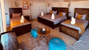 A cozy, tented room with a bed, sofa, ottoman, and a small table. - Nore luxury camp (Taouz)