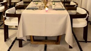 A tented dining area with tables set for a meal, chairs, and a hanging light fixture. - Nore luxury camp (Taouz)