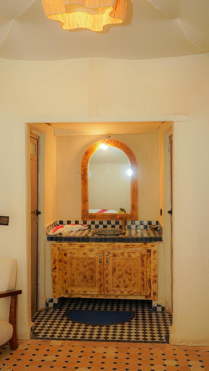 A bathroom with a wooden vanity, a mirror, and a patterned floor.
