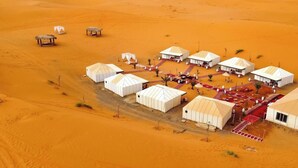 A desert camp with yurts arranged in a semi-circle, connected by pathways. - Nore luxury camp (Taouz)