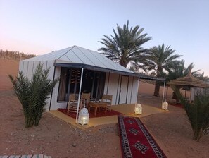 A desert tent with a covered patio, seating area, and decorative lanterns.
