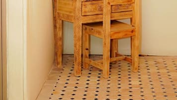 Ein Holzausziehtisch mit Spiegel und zwei Vasen mit Trockenpflanzen an einer Wand.