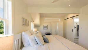 Un dormitorio con una cama grande, un ventilador de techo y una ventana con cortinas.